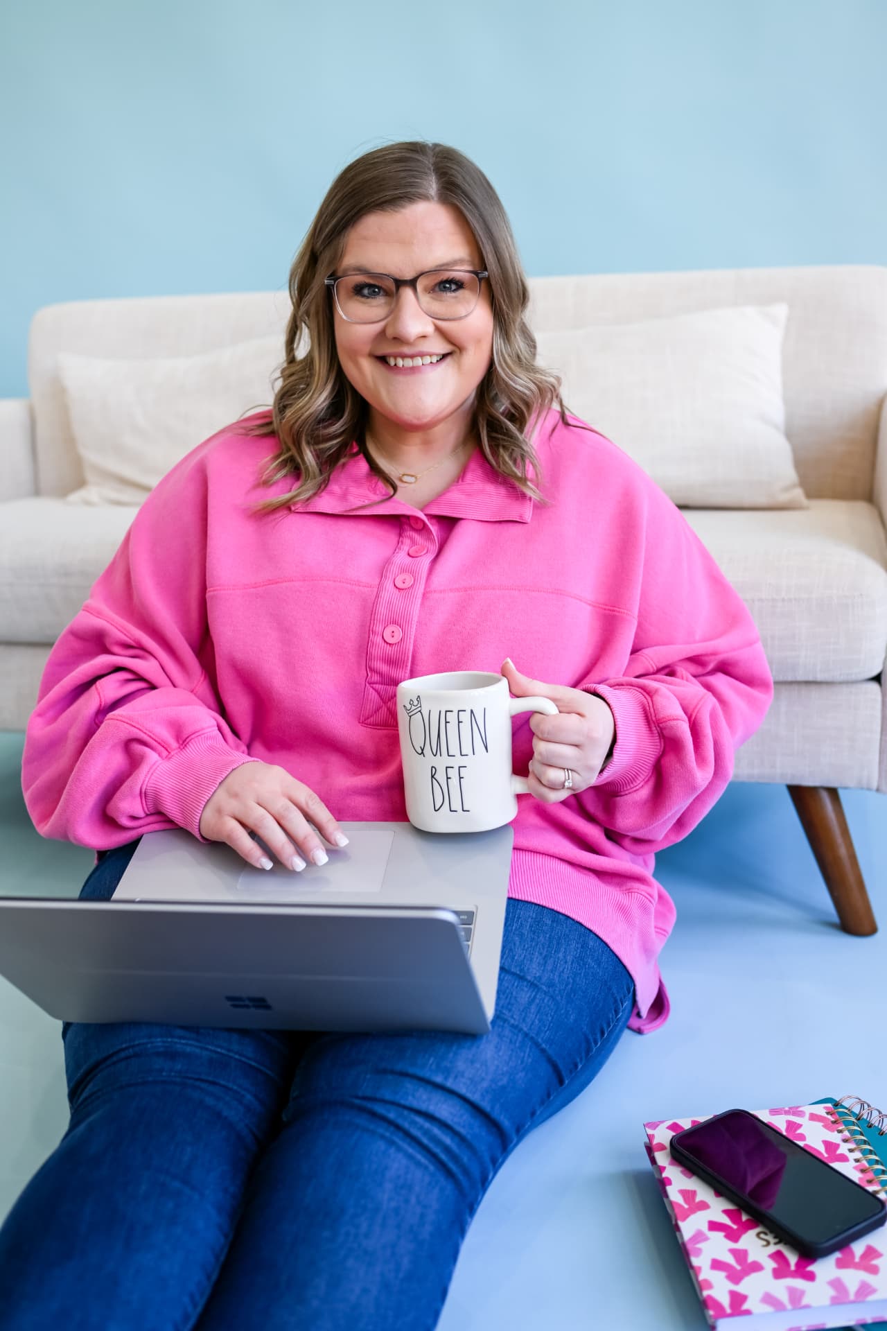Shelb smiling with her Queen Bee mug at her laptop